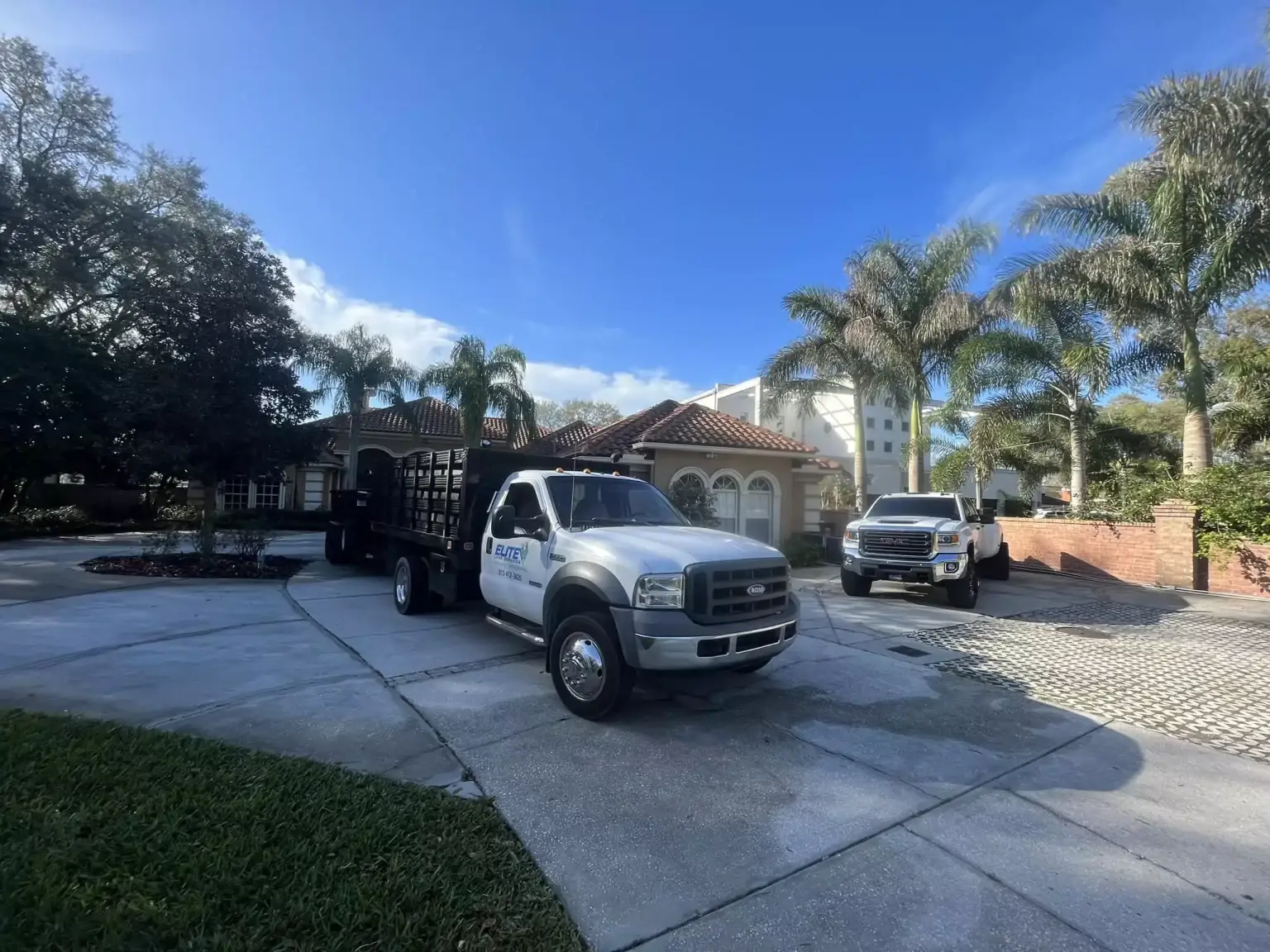 Elite Land Services trucks parked in the driveway of a landscaping client's home in Tampa